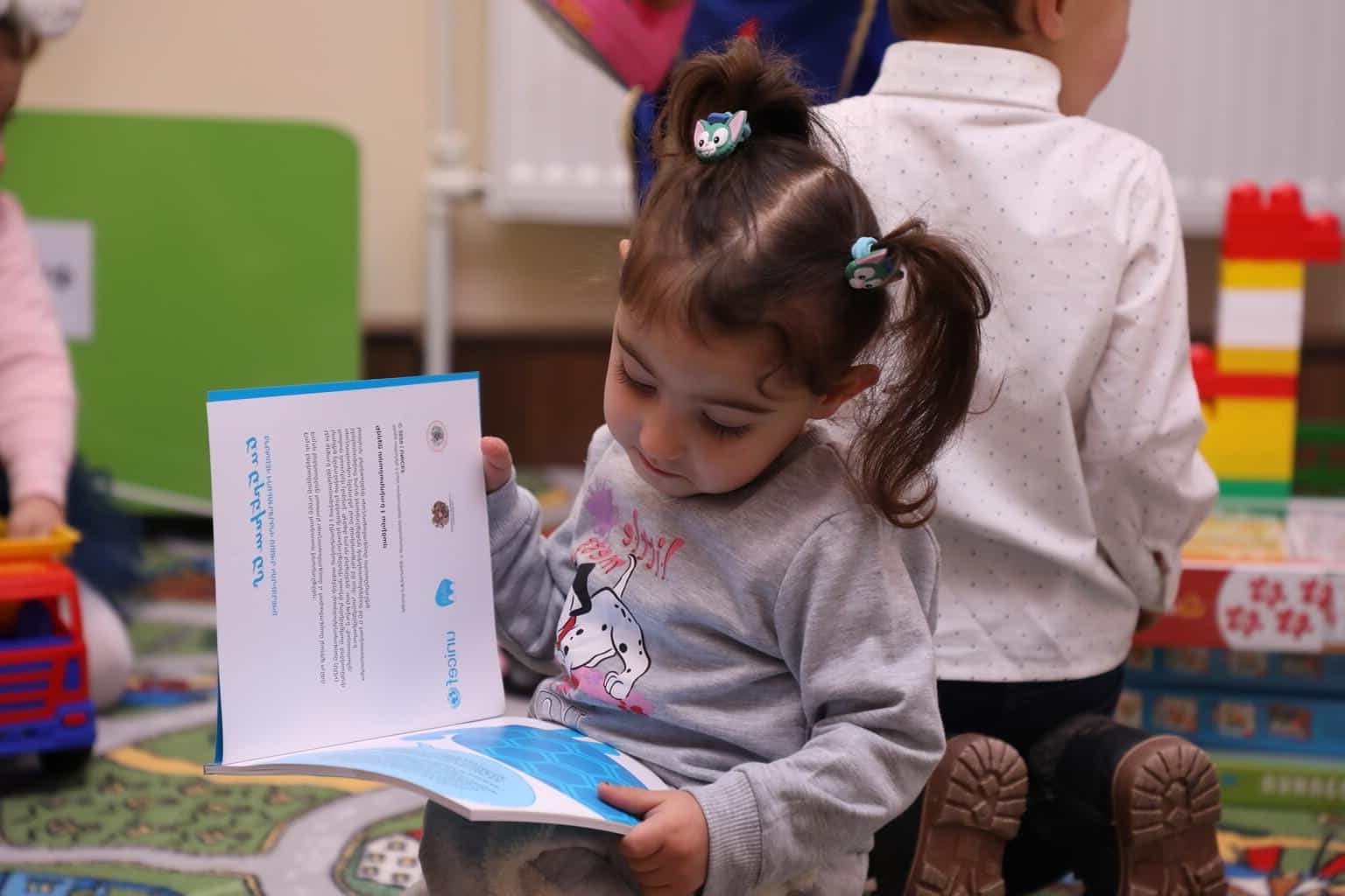 Une petite fille lit un livre dans le nouveau centre d'éducation préscolaire mis en place par l'UNICEF Arménie, le 21 décembre 2022. © UNICEF/UN0766924/Martirosyan