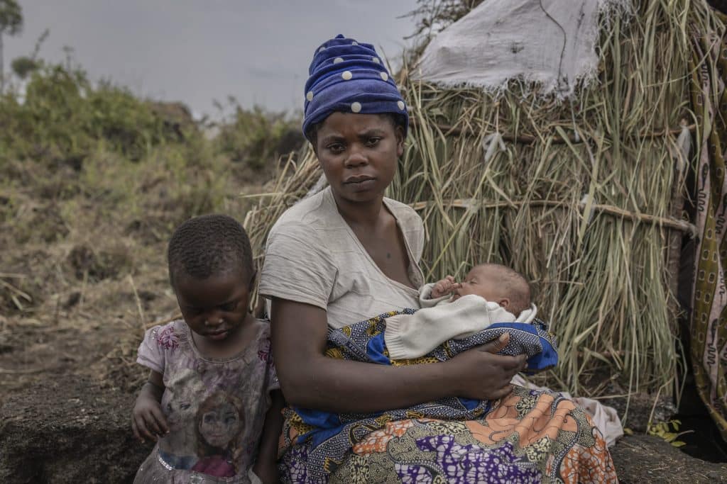 Fazili Muhunde tient son bébé Plamedi devant son abri au camp de Bulongo pour personnes déplacées dans la province du Nord-Kivu, République Démocratique Congo, le 8 février 2023.