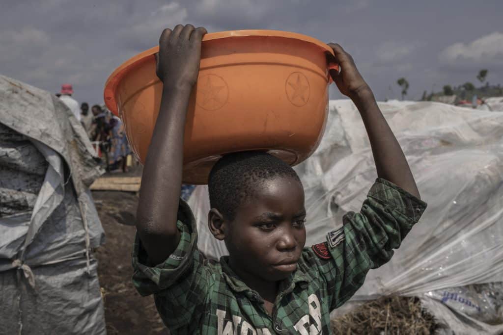 Merci Shivima, 12 ans, transporte une bassine d'eau dans le camp de déplacés de Bulengo, dans l'est de la République Démocratique Congo, le 08 février 2023.