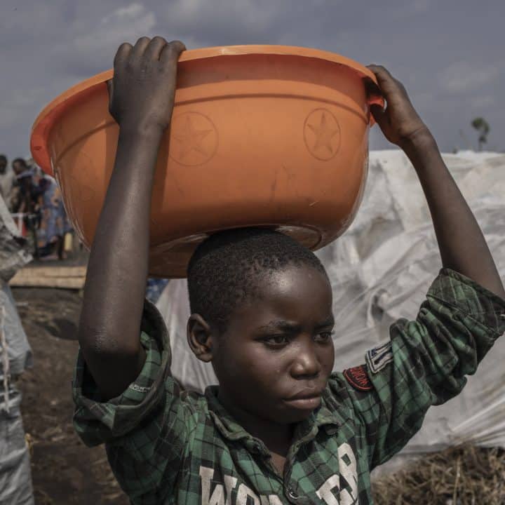 Merci Shivima, 12 ans, transporte une bassine d'eau dans le camp de déplacés de Bulengo, dans l'est de la République démocratique Congo, le 08 février 2023. © UNICEF/UN0791491/Ndebo