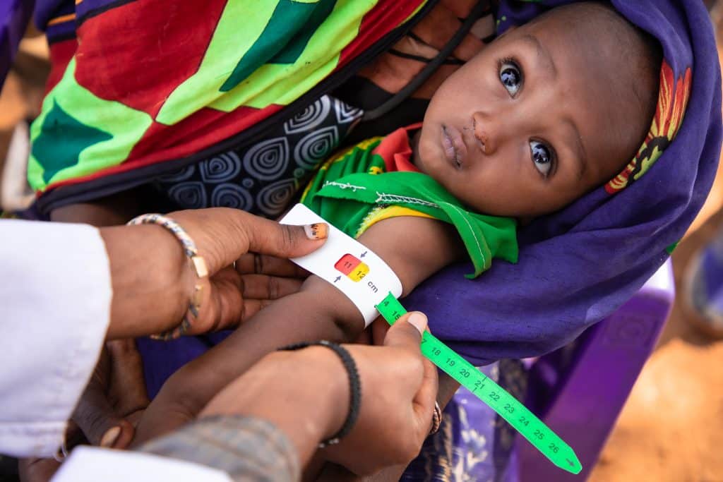 Une mère fait examiner le périmètre brachial de son bébé pour voir s'il souffre de malnutrition.