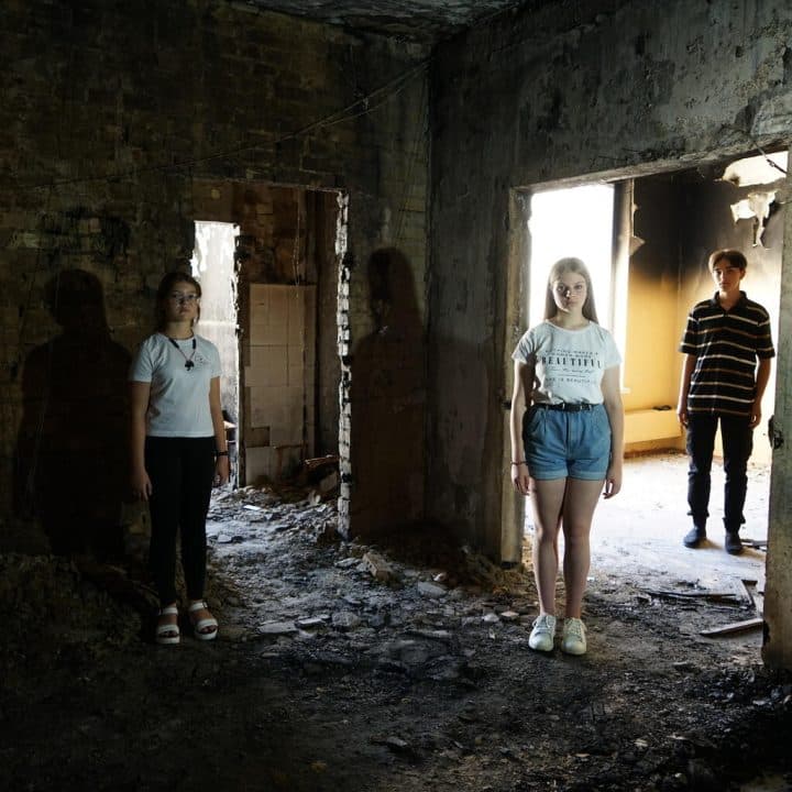 Le 22 juillet 2022 à Irpin, en Ukraine, Katya, 11 ans (à gauche), Arina, 15 ans (au centre), et Yaroslav, 15 ans (à droite), se tiennent à l'intérieur de leur école, qui a subi de lourds bombardements en mars 2022. ©UNICEF/UN0691707/Hrom