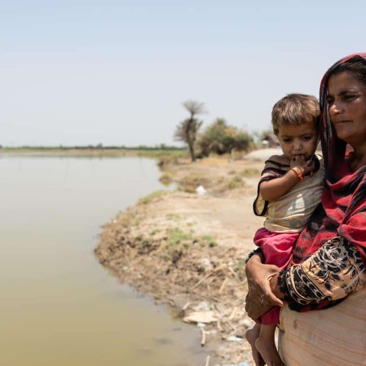 Benazir se tient avec sa fille à côté de l'eau stagnante qui subsiste plus de 6 mois après les inondations dévastatrices de 2022, au Pakistan.©UNICEF/UN0847811/Haro