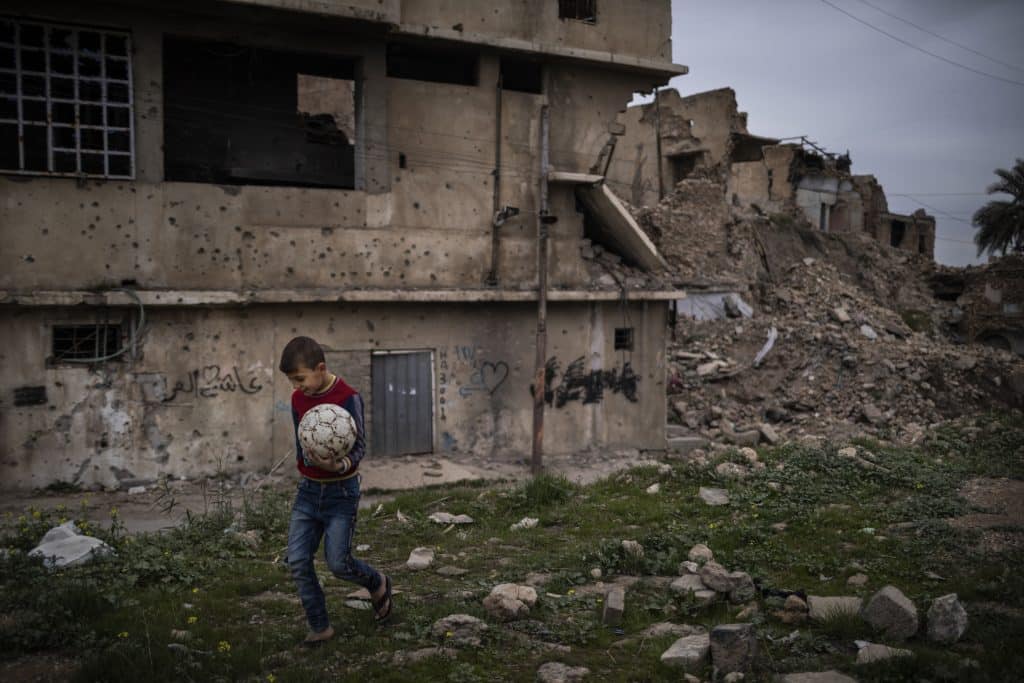 Le 6 mars 2022 en Irak, un garçon porte un ballon de football dans la ville de Mossoul. La plupart des quartiers sont en ruines à cause du conflit, mais peu à peu les populations reviennent, malgré le manque de services publics tels que l'eau courante et les égouts fonctionnels. © UNICEF/UN0611864/Ibarra Sánchez