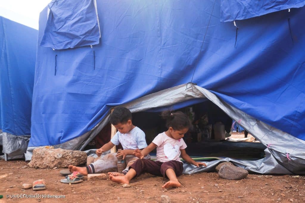 Le 12 septembre 2023, à Asni, au Maroc, des enfants jouent devant l'une des tentes fournies par le gouvernement dans un camp pour les familles qui ont perdu leur maison lors du violent tremblement de terre qui a secoué le pays le 8 septembre 2023. © UNICEF/UNI435150/Benkirane