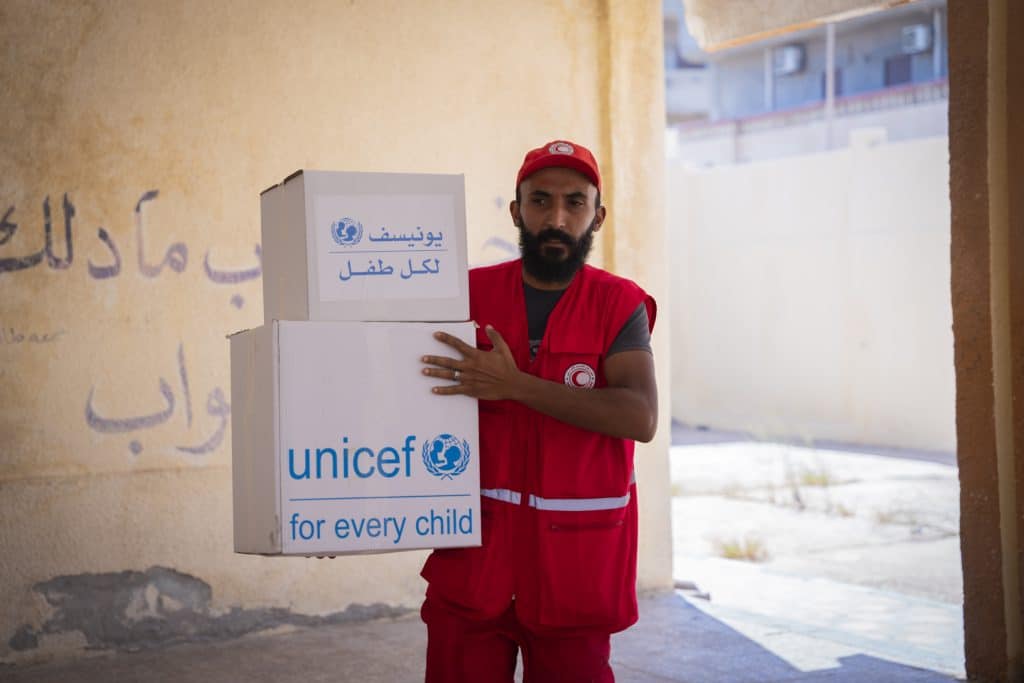 Le 16 septembre 2023, un membre du Croissant-Rouge libyen, partenaire de l'UNICEF, transporte des cartons de kits d'hygiène dans une école abritant les personnes touchées par les inondations à Derna, dans l'est de la Libye. ©UNICEF/UNI437851/Werfalli