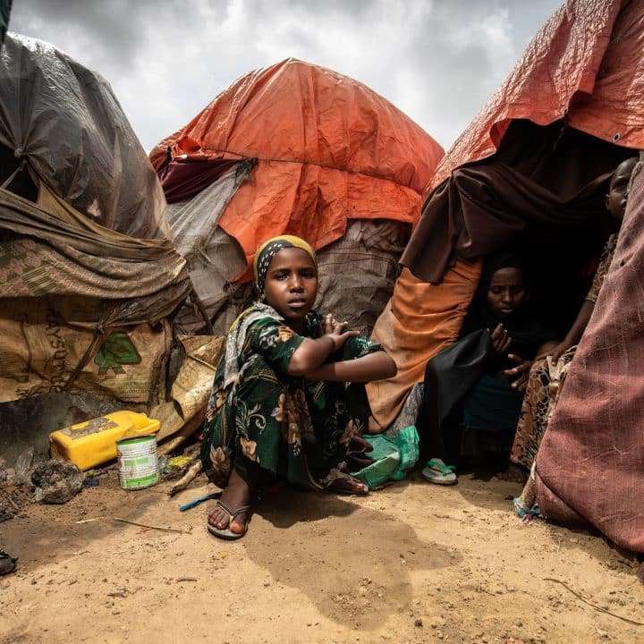 Une jeune fille est assise à l'extérieur de la tente dans laquelle vit sa famille dans un camp de personnes déplacées à Mogadiscio, en Somalie, en octobre 2022. © UNICEF/UN0742088/Condren