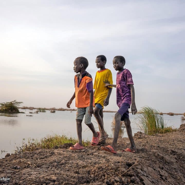 Le 27 février 2023, des garçons passent devant des champs inondés à Bentiu, dans l'État de l'Unité, au Soudan du Sud. © UNICEF/UN0836941/Naftalin