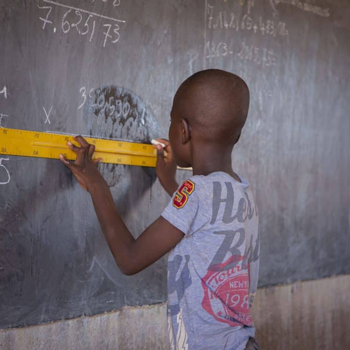 Un élève utilise une règle sur le tableau noir en classe, dans une école publique de Kaya, région Centre Nord, Burkina Faso.©UNICEF/UNI443917/Cisse