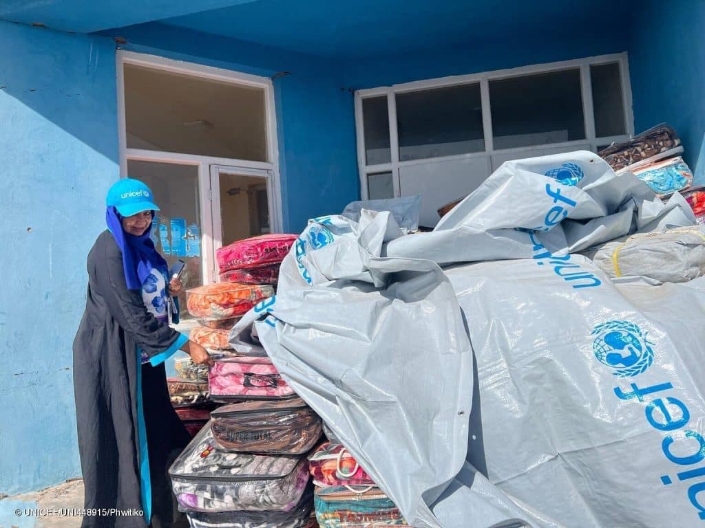 Le 8 octobre 2023, Tahani, spécialiste de la protection de l'enfance à l'UNICEF, se tient près des couvertures et des bâches distribuées aux familles par l'UNICEF dans le village de Seyab, dans le district d'Hérat, en Afghanistan. © UNICEF/UNI448915/Phwitiko