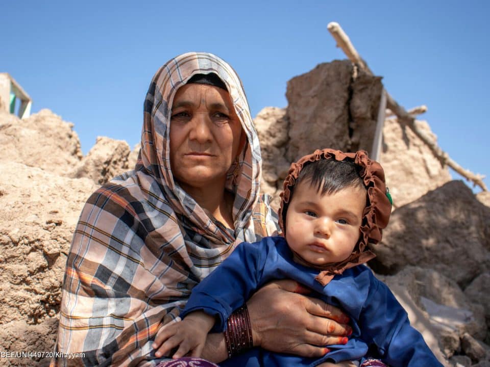 Le 9 octobre 2023, Ziba tient un petit garçon de 6 mois au milieu des décombres dans le district de Zinda Jan, dans la province de Herat, en Afghanistan, après le tremblement de terre survenu deux jours auparavant. © UNICEF/UNI449720/Khayyam