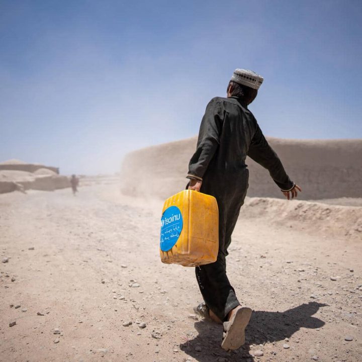 Un garçon ramène chez lui un jerrycan rempli d'eau, recueillie à un point d'eau soutenu par l'UNICEF dans le village de Noorkhail, district de Muqur, dans la province de Badghis, en Afghanistan, en juin 2023. ©UNICEF/UN0855414/Naftalin
