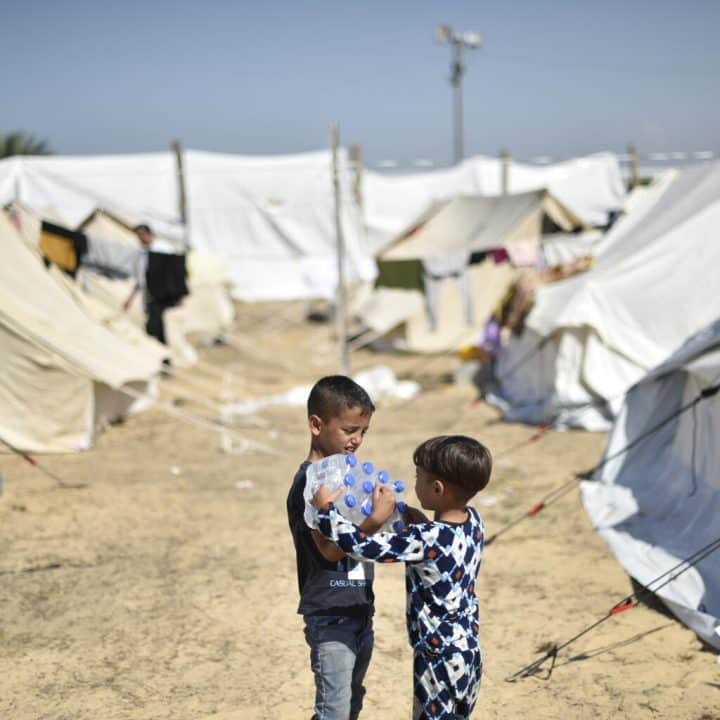 Yamen, 7 ans, et son frère Yazan, 4 ans, transportent des bouteilles d'eau fournies par l'UNICEF dans le camp de réfugiés de l'UNRWA à Khan Yunis, dans le sud de la bande de Gaza. ©UNICEF/UNI472261/Zaqout