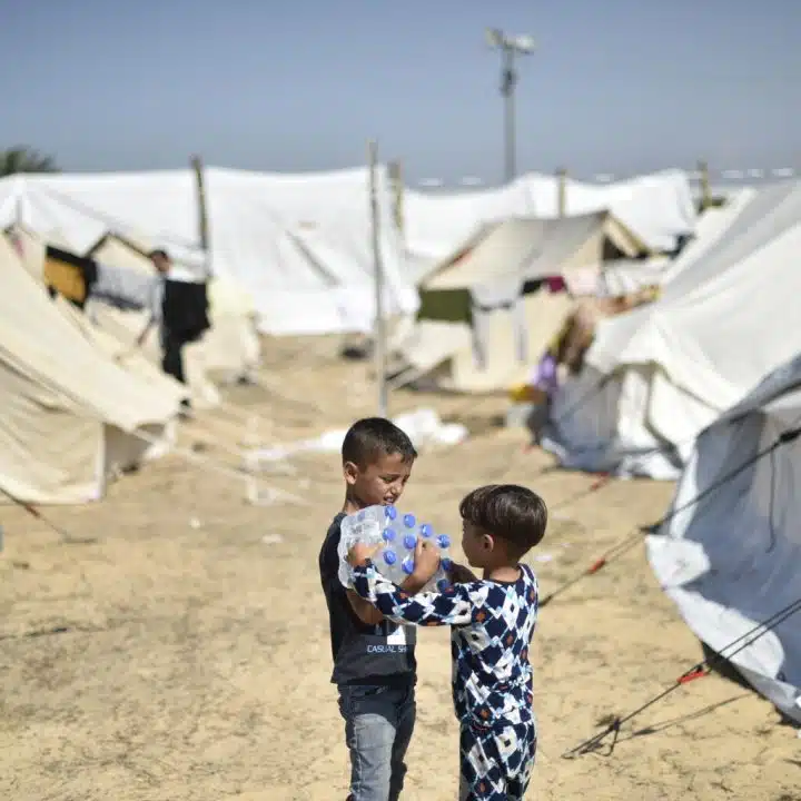 Yamen, 7 ans, et son frère Yazan, 4 ans, transportent des bouteilles d'eau fournies par l'UNICEF dans le camp de réfugiés de l'UNRWA à Khan Yunis, dans le sud de la bande de Gaza. ©UNICEF/UNI472261/Zaqout