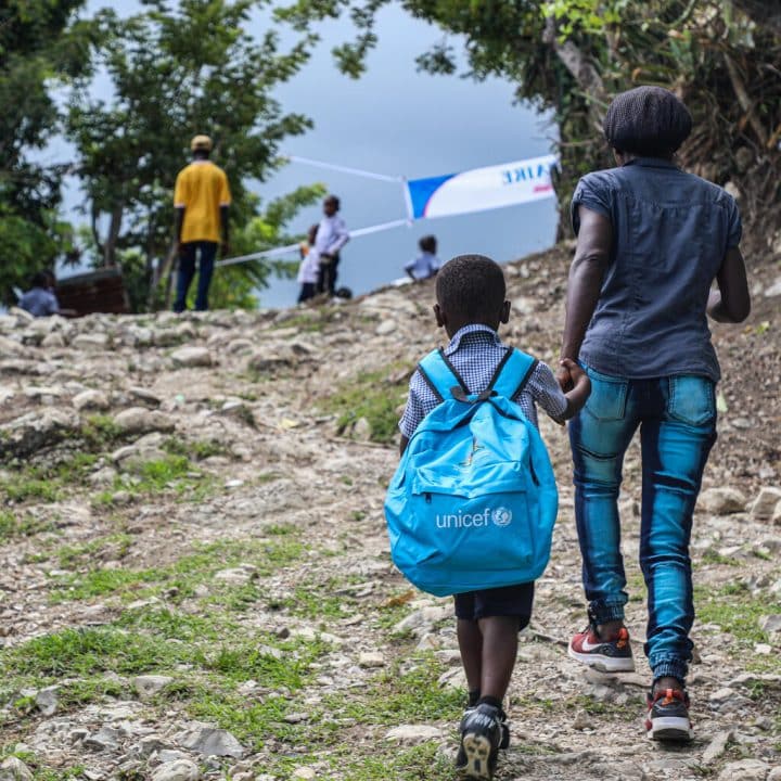 Un parent accompagne son enfant à l'école récemment reconstruite grâce à l'UNICEF dans la communauté de Jaquin, département de la Grand'Anse, en Haïti. ©UNICEF/UNI465833/Joseph