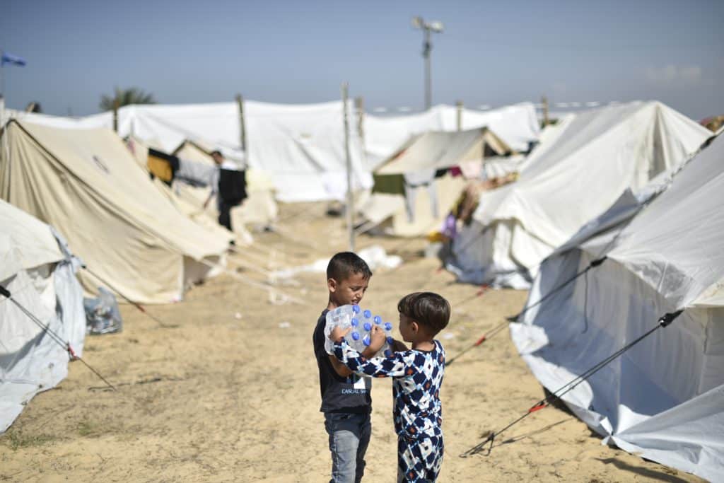 Yamen, 7 ans, et son frère Yazan, 4 ans, transportant des bouteilles d'eau distribuées par l'UNICEF dans le camp de réfugiés de l'UNRWA à Khan Yunis, au sud de la bande de Gaza. © UNICEF/UNI472261/Zaqout