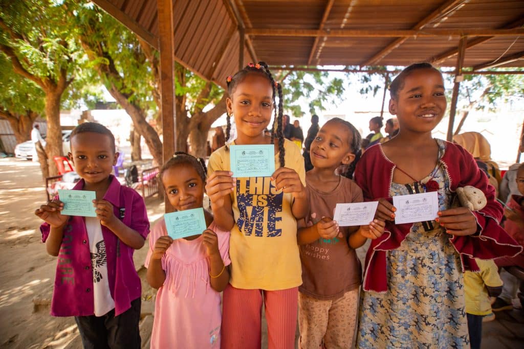 Le 21 novembre 2023, des enfants montrent leur carte de vaccination après avoir reçu des doses de vaccin contre le choléra lors d'une campagne de vaccination contre le choléra dans l'État de Madani Gezira. L'UNICEF soutient la campagne de vaccination contre le choléra du ministère fédéral de la Santé dans les États touchés, y compris celui de Gezira.© UNICEF/UNI476505/Mohamdeen