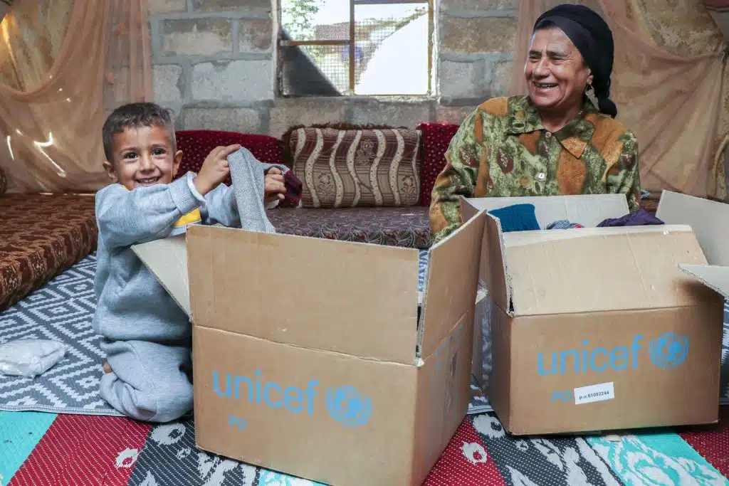 Le 5 octobre 2021, Rashid, 4 ans, et sa grand-mère Alia, découvrent le contenu des kits urgence de l'UNICEF dans le camp de Fafin, au nord de la zone rurale d'Alep. © UNICEF/UN0581234/Almatar