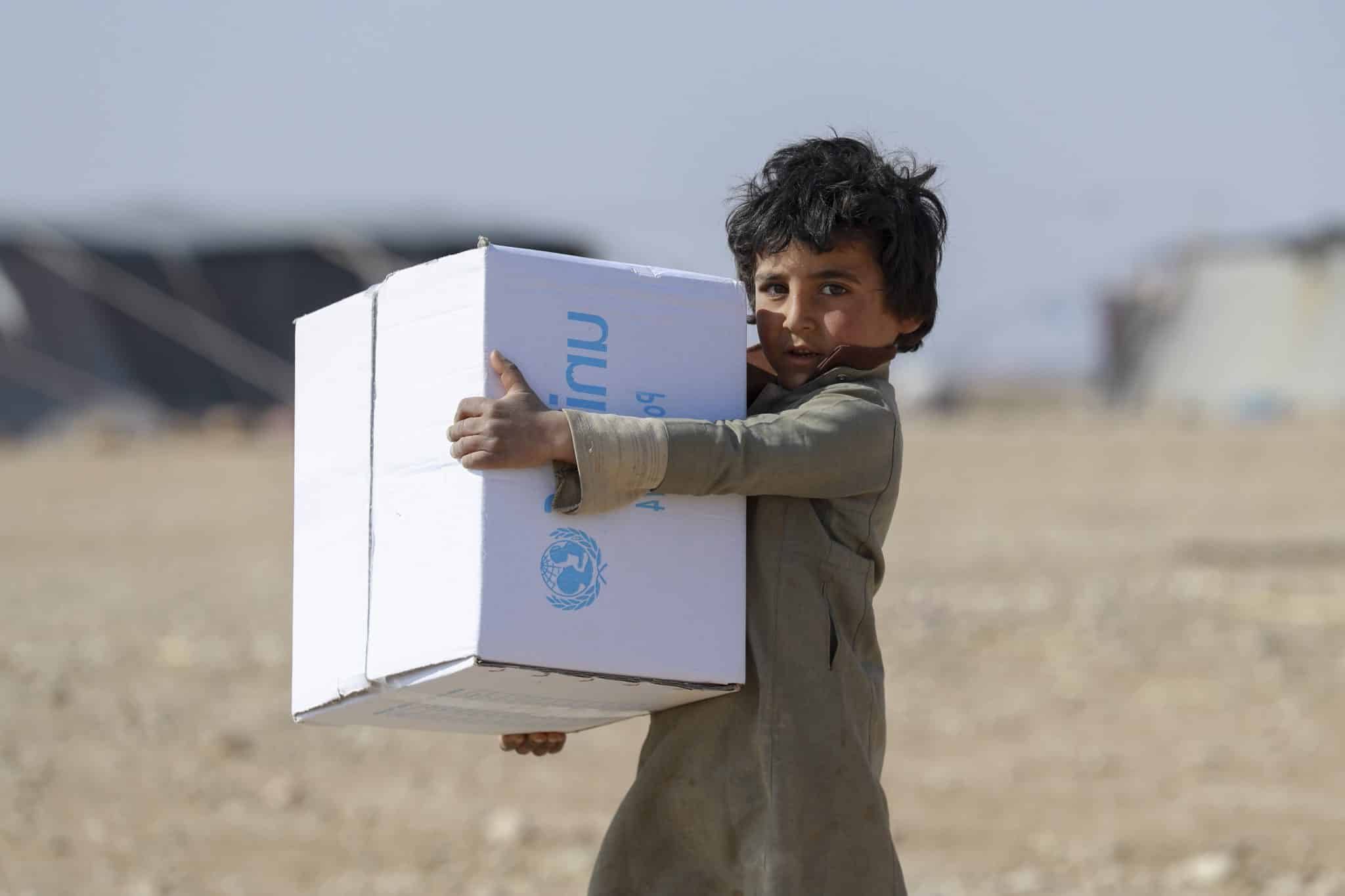 Des enfants déplacés aident leurs parents lors de la distribution de vêtements d'hiver dans le quartier de Kabish Wasti, à Raqqa, en Syrie, le 16 février 2022.© UNICEF/UN0612164/Souleiman