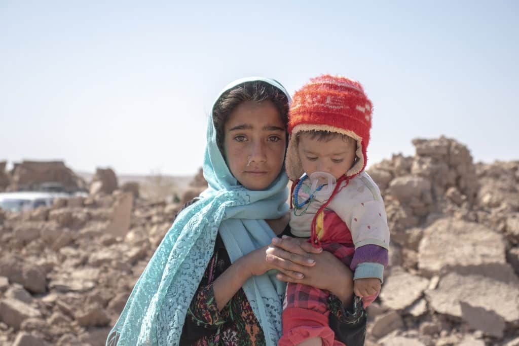 Le 10 octobre 2023, Zari, 10 ans, tient dans ses bras son frère Marv, 8 mois, après que leur maison a été détruite par le tremblement de terre dans le district de Zinda Jan, en Afghanistan. © UNICEF/UNI452497/Khayyam