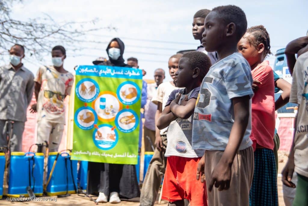 Des équipes de l'UNICEF et ses partenaires expliquent aux enfants de la ville de Gedaref le contenu d'une affiche sur la prévention du choléra, y compris le lavage des mains avec de l'eau et du savon. © UNICEF/UNI454316/Tarig