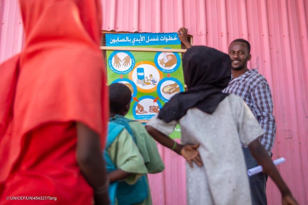 Des équipes de l'UNICEF et ses partenaires expliquent aux enfants de la ville de Gedaref le contenu d'une affiche sur la prévention du choléra, y compris le lavage des mains avec de l'eau et du savon. © UNICEF/UNI454327/Tarig