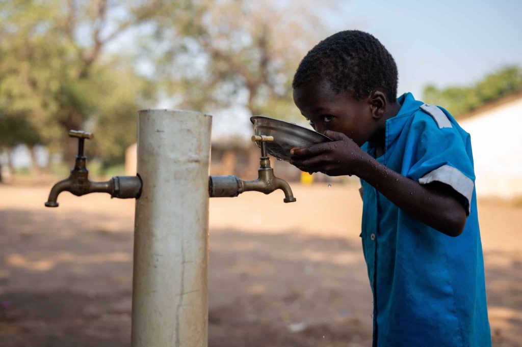 Portrait d'un élève buvant de l'eau potable grâce aux installations soutenues par l'UNICEF. Dans la région de Kalima, au Malawi, l'accès à l'eau potable est un défi. Entre 2022 et 2023, le pays a été frappé de plein fouet par la pire épidémie de choléra depuis 20 ans. Près de 60 000 personnes ont été touchées © UNICEF/UNI466232/Khanyizira