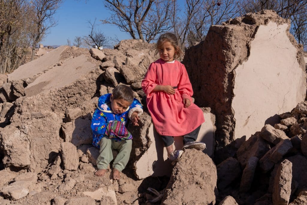 Le 3 décembre 2023, des enfants se font photographier sur un tas de décombres où se trouvait leur maison avant les tremblements de terre qui ont ravagé l'Afghanistan. © UNICEF/UNI485389/Karimi