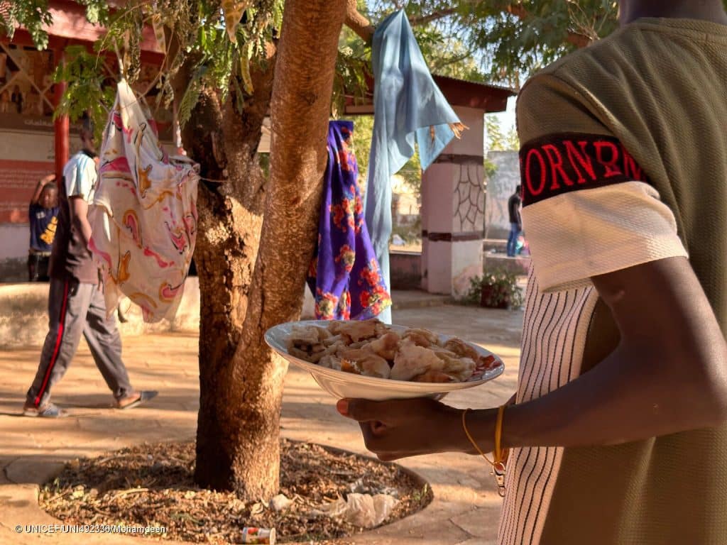 Un jeune porte une assiette de nourriture, le 18/12/2023. © UNICEF/UNI492336/Mohamdeen