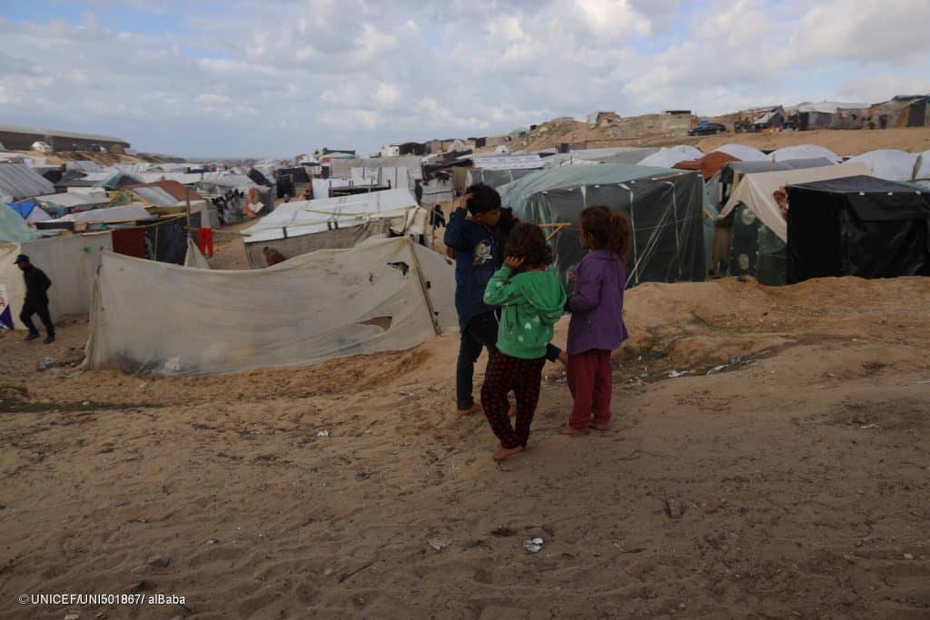 Le 11 janvier 2024, un groupe d'enfants se rassemble près des tentes pour les personnes déplacées dans la bande de Gaza. © UNICEF/UNI501867/ alBaba