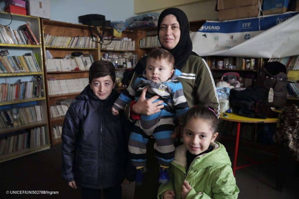 Le 13 janvier 2024, Mohammed, 10 ans, à gauche, Obaida, 1 an, au centre, et Yasmina, 6 ans, à droite, posent avec leur mère Israa pour une photo au Centre des femmes de Rafah, dans le sud de Gaza, actuellement utilisé comme abri, après la distribution de manteaux d'hiver, achetés par l'UNICEF. © UNICEF/UNI502768/Ingram