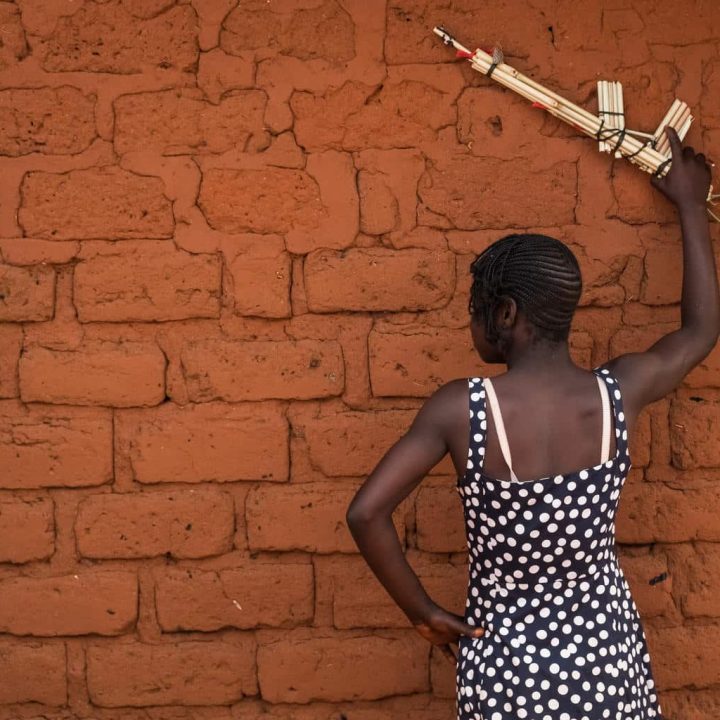 Elodie, 13 ans, anciennement associée au groupe armé anti-balaka, tient une arme factice en marge d'une cérémonie marquant la création d'un centre de formation professionnelle et de réadaptation pour les enfants anciennement associés à des groupes armés devant la mairie de Baoro, en République centrafricaine, mercredi 1er novembre 2017. ©UNICEF/UN0149462/Sokhin