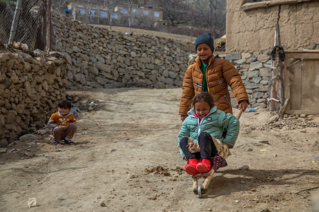 Shamsuddin, 7 ans, joue avec sa soeur Sahar, 6 ans, après avoir reçu de nouveaux manteaux et bottes d'hiver grâce à un kit de vêtements de l'UNICEF, le 14 mars 2023 à Panjshir, en Afghanistan. © UNICEF/UN0804343/Haya Burhan