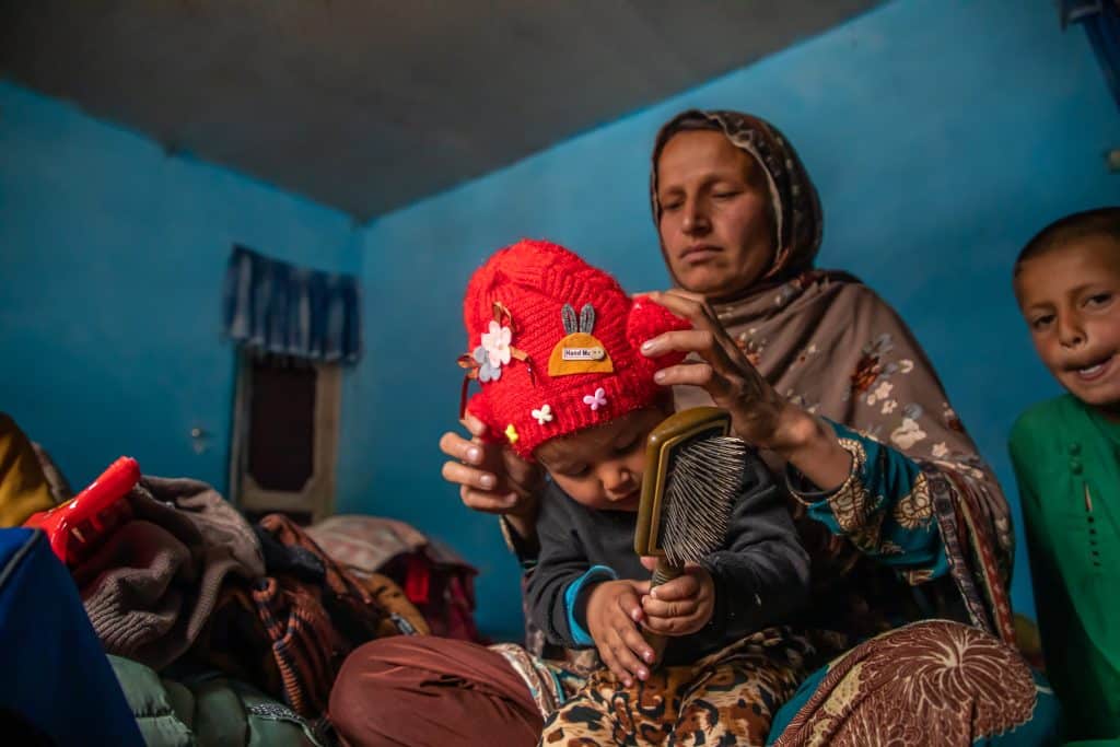 Le 14 mars 2023, Razia habille sa fille de 11 mois, Bahara, avec un nouveau bonnet d'hiver qu'elles ont reçu grâce à un kit de vêtements d'hiver de l'UNICEF, dans la province de Panjshir, en Afghanistan. © UNICEF/UN0804374/Meerzad