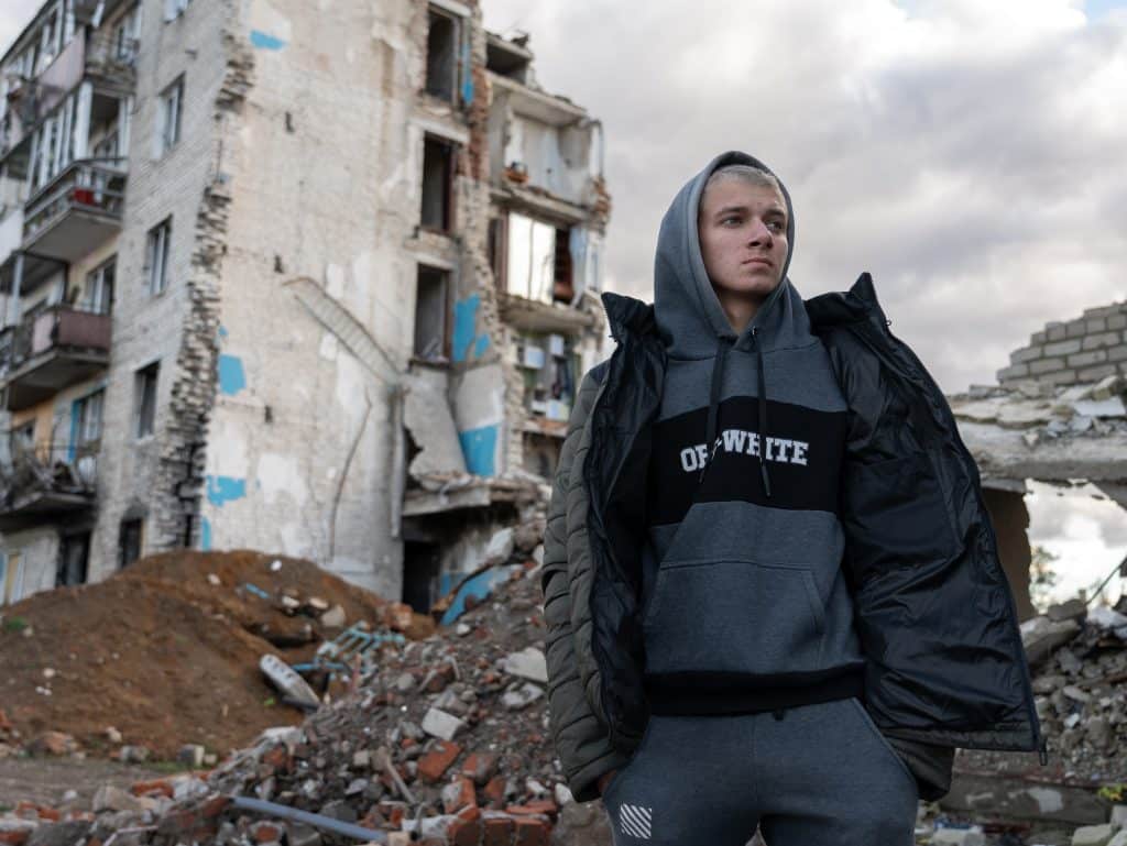 Le 28 octobre 2023 à Izium en Ukraine, Habriel, 17 ans, se tient devant un bâtiment détruit par les bombardements. © UNICEF/UNI484041/Filippov
