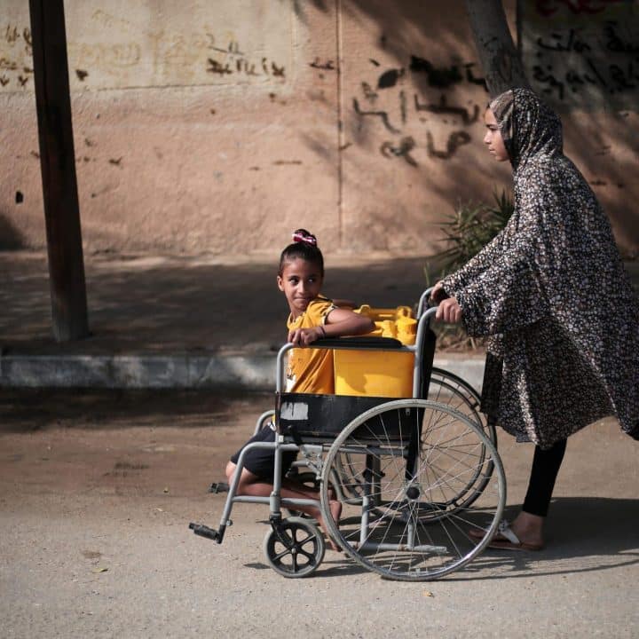 Palestinian girls use a wheelchair to carry water in Khan Younis city, southern Gaza Strip. © UNICEF/UNI485738/El Baba