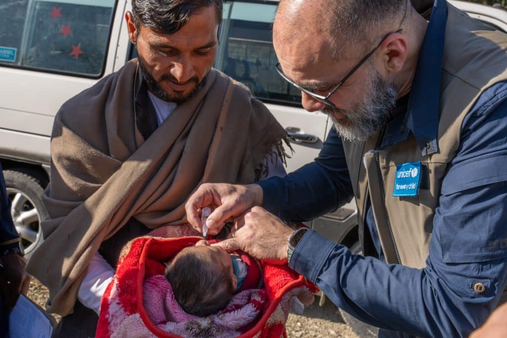 Le 4 décembre 2023, Naysán Sahba, directeur de la division de la communication mondiale et du plaidoyer de l'UNICEF, administre une dose de vaccin oral contre la polio à un enfant au poste frontière de Torkham, dans la province de Nangarhar, en Afghanistan.© UNICEF/UNI486233/Karimi