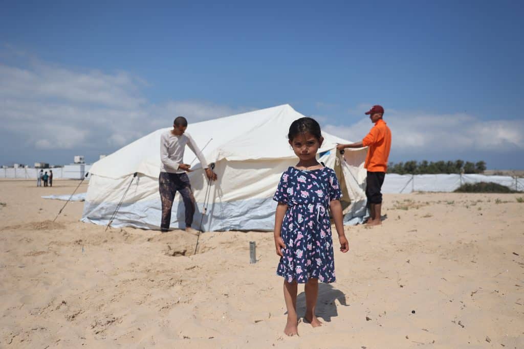 Une fillette se tient devant la tente que sa famille dans le sud de la bande de Gaza.© UNICEF/UNI556607/El Baba