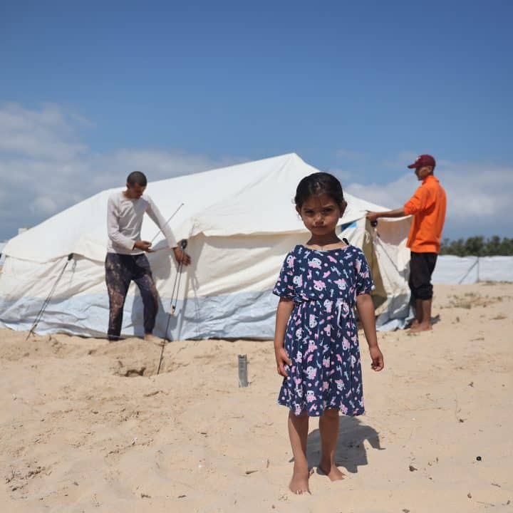 Une fillette se tient devant la tente que sa famille dans le sud de la bande de Gaza.© UNICEF/UNI556607/El Baba