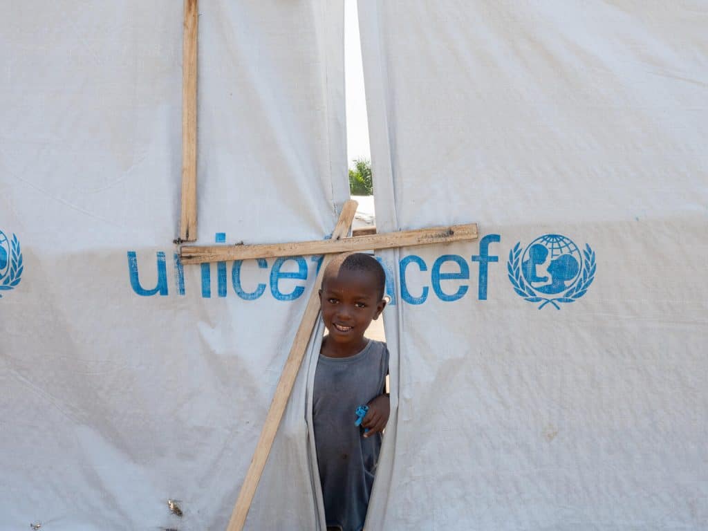 Un petit garçon se tient devant une tente dans le site de déplacés de Sobel au Burundi.© UNICEF/UNI486005/Freese