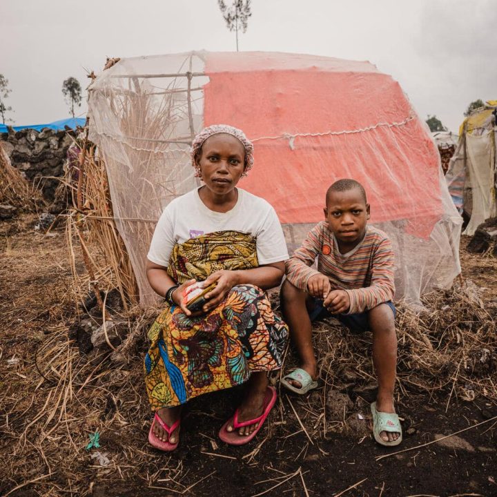 Le 27 février 2024, Aline et son fils Justin âgé de 6 ans sont assis devant leur tente dans le camp de déplacés de Buhimba-Mabanga près de Goma, dans la province du Nord-Kivu, en République démocratique du Congo © UNICEF/UNI538389/Benekire