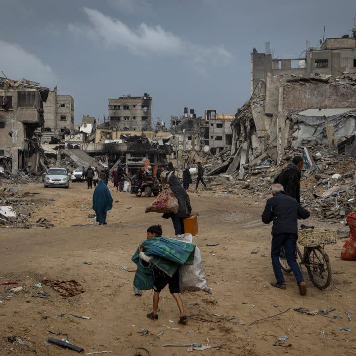 People including children carry their belongings while they walk through the rubble of destroyed houses in Khan Younis, southern the Gaza Strip. © UNICEF/UNI544681/El Baba
