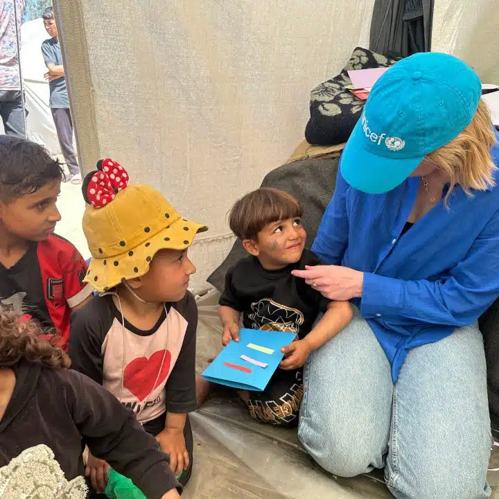 Le 3 avril 2024, à Rafah, dans le sud de la bande de Gaza, Tess Ingram, porte-parole de l'UNICEF, interagit avec des enfants participant à des activités psychosociales dans le camp de Tel al Soltan Stadium. © UNICEF/UNI551189/Eliean