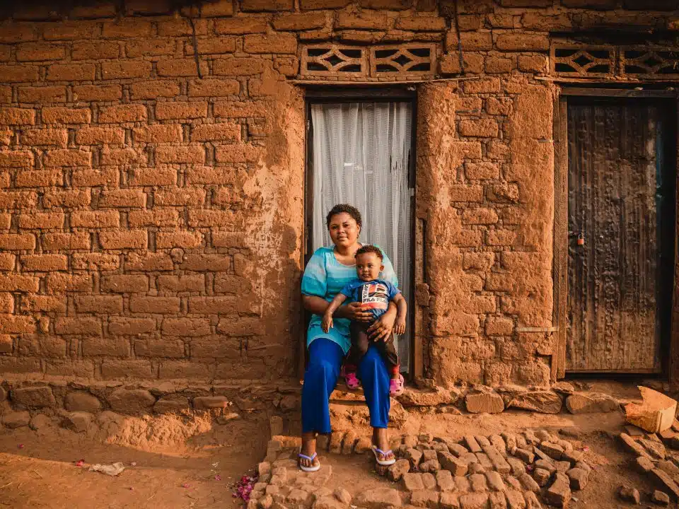 Gabriel, 1 an, est assis sur les genoux de sa mère Sarah à l'extérieur de leur maison à Kamanyola, dans la province du Sud-Kivu, en République démocratique du Congo. Le petit garçon a survécu à la mpox grâce à une prise en charge rapide à l'hôpital de Kamanyola, soutenu par l'UNICEF. © UNICEF/UNI624798/Benekire