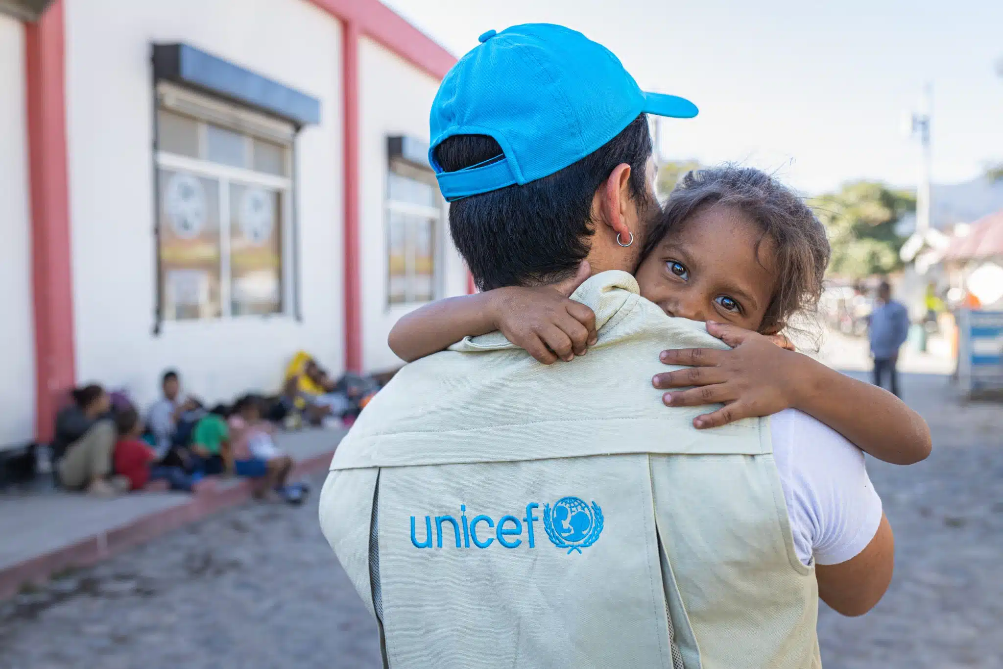 Le 26 février 2024, au Guatemala, Mario Gamarro, consultant en communication de l’UNICEF, prend Nicole, 8 ans, dans ses bras après avoir que la petite fille ait été examinée par une unité mobile de soin soutenue par l’UNICEF. © UNICEF/UNI694965/Willocq