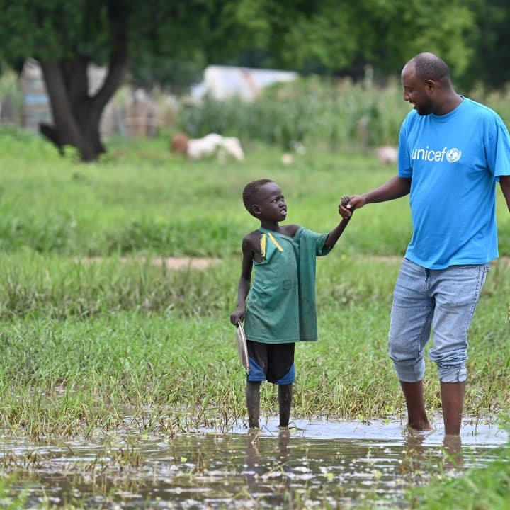 Un membre du staff de l'UNICEF et un enfant se frayent un chemin à Malow, en Ethiopie après que le village ait été inondé. © UNICEF/UNI594324/Dejongh