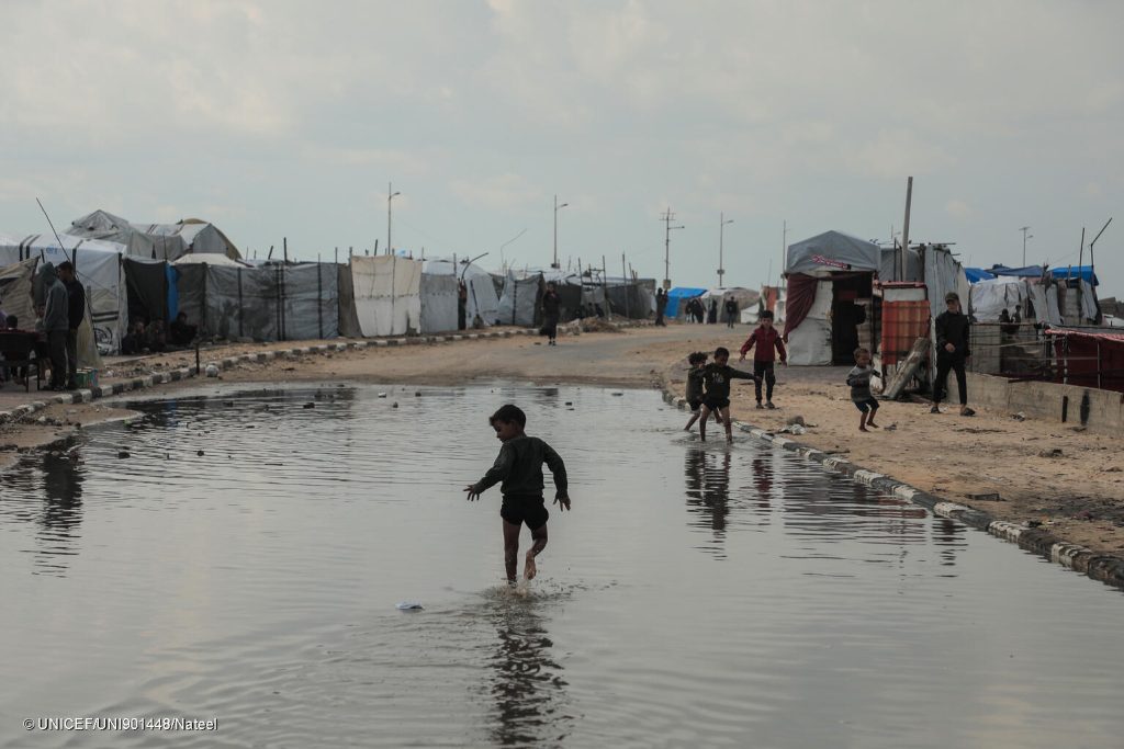 [Gaza conflit] Un enfant joue dans l'eau de pluie dans le quartier de la rue Al-Rashid, dans la bande de Gaza, le 14/11/2025. © UNICEF/UNI901448/Nateel