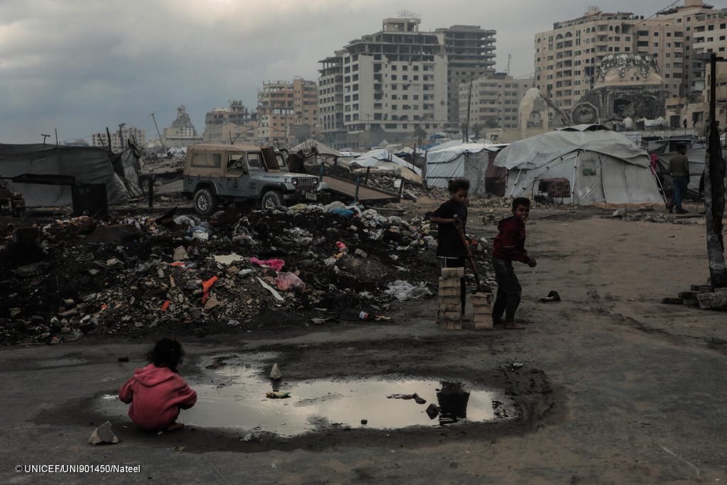 Des enfants jouent dans l'eau de pluie dans le quartier de la rue Al-Rashid, dans la bande de Gaza, le 14/11/2025. © UNICEF/UNI901450/Nateel