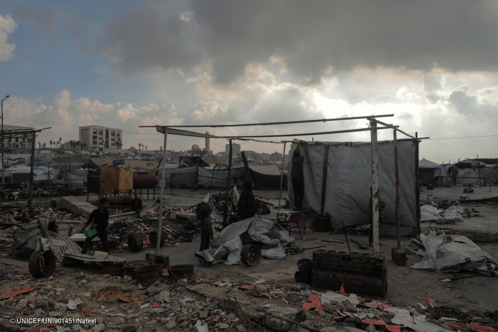 Une famille répare sa tente après qu'elle ait été endommagée par la pluie et les vents violents dans la zone portuaire de Gaza. © UNICEF/UNI901451/Nateel