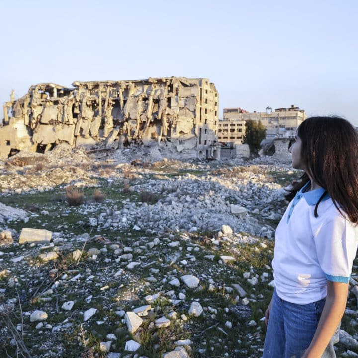 Nour, 13 ans, se tient devant les destructions massives à Alep, en Syrie, le 17 février 2025. © UNICEF/UNI763314/Ashawi